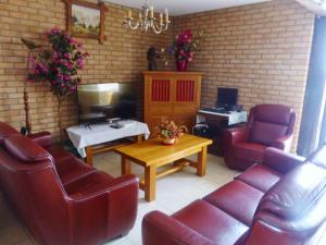 - un salon avec des fauteuils en cuir rouge et une télévision dans l'établissement Gite de vieille maison rouge, à Rocroi
