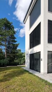 biały budynek z dwoma drzwiami garażowymi obok trawnika w obiekcie Seabreeze Luxury Apartments w mieście Nijvice