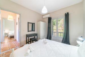 Un dormitorio con una gran cama blanca y una ventana en Agia Sana house Gardenos, en Vitalades