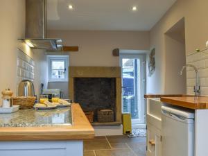 a kitchen with a fireplace in the middle of a room at Corner Cottage in Great Longstone