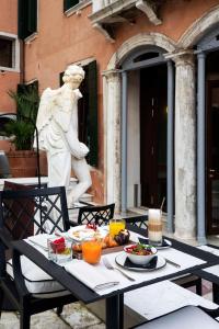 a table with a plate of food and a statue at Radisson Collection Hotel, Palazzo Nani Venice in Venice