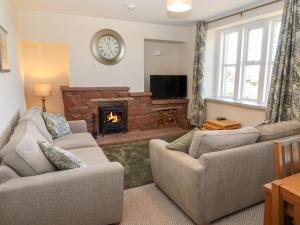 a living room with two couches and a fireplace at Rose Bank Cottage in Carlisle