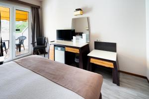 um quarto de hotel com uma cama e uma secretária com uma televisão em Byzantio Hotel em Tessalônica