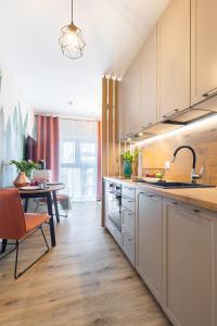 a kitchen with white cabinets and a dining room with a table at Apartamenty Jaworska 4 Wrocław in Wrocław