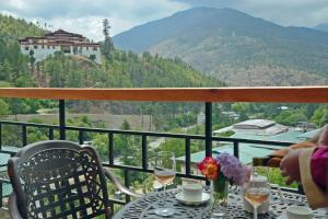 a table with wine glasses and flowers on a balcony at Cholay Khangzang in Thimphu