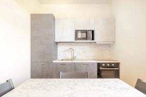 eine Küche mit weißen Schränken, einem Tisch und einer Mikrowelle in der Unterkunft Appartamento Michelangelo in Prato