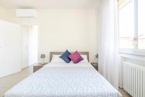 - une chambre avec un lit blanc et 2 oreillers violets dans l'établissement Appartamento Michelangelo, à Prato