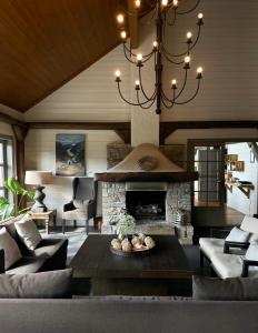 a living room with a stone fireplace and a chandelier at Bjørnafjorden Hotell in Osøyro