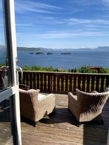 two wicker chairs sitting on a deck looking out at the ocean at Bjørnafjorden Hotell in Osøyro