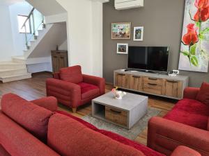 a living room with red chairs and a flat screen tv at Vacation House in Draç