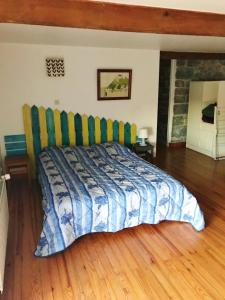 een slaapkamer met een bed met een blauwe en groene deken bij Les jonquilles in Rancennes