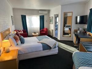 Habitación de hotel con cama y sala de estar. en Grand Country Lodge Motel, en Mittagong