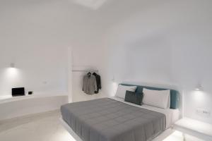 biała sypialnia z łóżkiem z niebieskim zagłówkiem w obiekcie White Concept Caves w Firze