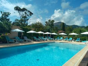 a swimming pool with chairs and umbrellas at Le Râteau Bavoir in Calvi