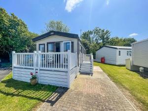 a small house with a white fence and a porch at Beautiful Caravan With Decking At Carlton Meres Holiday Park, Suffolk Ref 60022m in Saxmundham