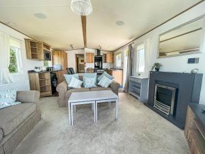 a living room with a couch and a fireplace at Beautiful Caravan With Decking At Carlton Meres Holiday Park, Suffolk Ref 60022m in Saxmundham