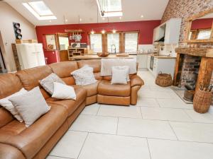 ein Wohnzimmer mit einem braunen Sofa und einer Küche in der Unterkunft 4 Pheasant Lane in Sheffield