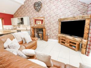 ein Wohnzimmer mit einem großen TV und einer Ziegelwand in der Unterkunft 4 Pheasant Lane in Sheffield