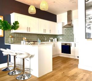 a kitchen with white cabinets and white bar stools at 15 Kingsway House in Worthing