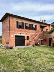 ein Backsteingebäude mit einer Garage und einem Rasenplatz in der Unterkunft La casa terra dei sogni in Castiglione del Lago