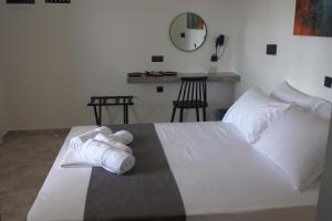 ein Schlafzimmer mit einem weißen Bett und Handtüchern darauf in der Unterkunft Petteo Serifos in Livadakia