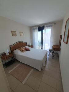 una camera da letto con un grande letto bianco e due sedie di Apartamento Cala y Mar ad Alicante