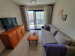 een woonkamer met een bank, een tv en een tafel bij Apartamento Cala y Mar in Alicante