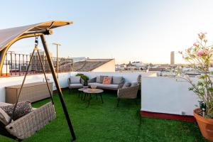 a rooftop patio with a couch and chairs and an umbrella at Ático con encanto en Sierpes in Seville