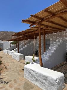 a row of white benches under a wooden roof at Rizes Mykonos - Folklore Farmstead in Mýkonos City