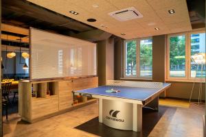a ping pong table in a room with windows at a&o Warszawa Wola in Warsaw