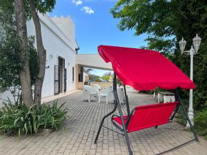 une chaise rouge assise sur un patio en briques dans l'établissement Il Casolare Degli Ulivi, à Oria