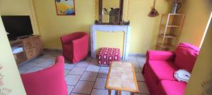a living room with pink furniture and a tv at L'esperance in Haybes