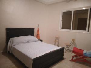 1 dormitorio con 1 cama, 1 silla y 1 ventana en Golden Beach, en Dar Hamida