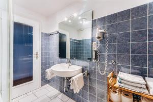 een blauw betegelde badkamer met een wastafel en een spiegel bij Weidegg - Hotel Garni in Garmisch-Partenkirchen