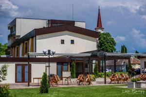 a building with tables and chairs in front of it at Hotel River in Luduş