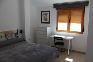 a bedroom with a bed and a desk and a window at ÁTICO CENTRO in Yecla
