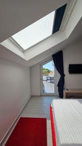 - une chambre avec une lucarne et un lit avec un tapis rouge dans l'établissement Apartments Villa Alba, à Dubrovnik