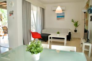 een woonkamer met een tafel en een rode stoel bij Yiallos Village Apt. A101 in Menevi