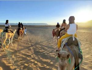 a group of people riding horses on the beach at Zagora luxury desert camp in Zagora