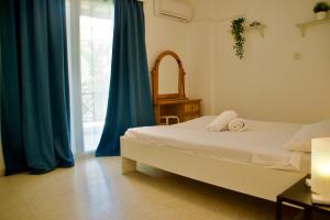 een slaapkamer met een bed met blauwe gordijnen en een raam bij Yiallos Village Apt. A101 in Menevi