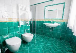 La salle de bains est pourvue de carrelage vert, de toilettes et d'un lavabo. dans l'établissement Hotel Villa Pandora, à Maiori