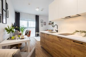 eine Küche mit Holzschränken und einer weißen Arbeitsplatte in der Unterkunft Apartamenty Jaworska 4 Wrocław in Breslau