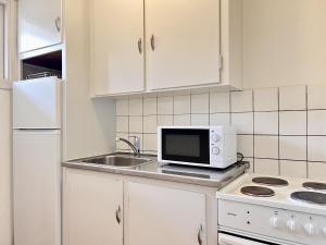 a white kitchen with a microwave and a sink at Studio Apartment In Herlev, Herlevgrdsvej 2, 4 in Herlev