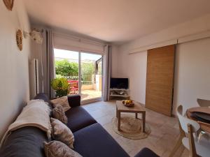 een woonkamer met een blauwe bank en een televisie bij Bel appartement rénové, avec terrasse et piscine in La Croix-Valmer