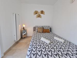 een slaapkamer met een bed met een zwart-witte sprei bij Bel appartement rénové, avec terrasse et piscine in La Croix-Valmer