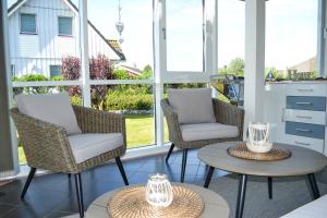 porche cubierto con 2 sillas y mesa en Modernes Ferienhaus direkt an der Nordsee, en Wesselburenerkoog