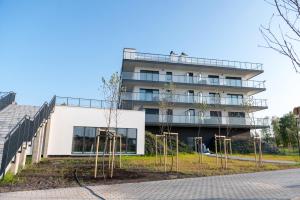 a white building with trees in front of it at Silver SPA - 22 in Dziwnów