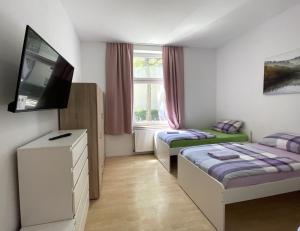 a small room with two beds and a flat screen tv at Gelsenkirchen, 2-Zimmer Wohnung , 6 Person in Gelsenkirchen