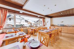 ein Restaurant mit Holztischen und -stühlen und einem großen Fenster in der Unterkunft Weidegg - Hotel Garni in Garmisch-Partenkirchen