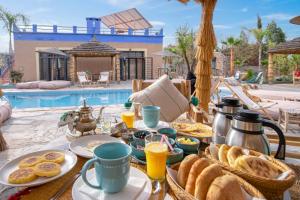 uma mesa com comida e bebidas ao pequeno almoço e uma piscina em La Fattoria Ecolodge em Lalla Takerkoust